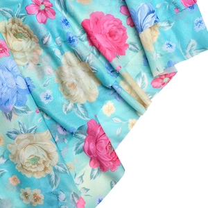 Detailed close-up of light blue floral mesh fabric with pink and yellow vintage prints