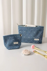 Detail of blue denim cosmetic bag set with heart bow pattern and flower zipper charm