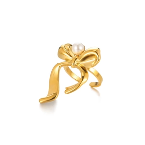 Detail of a golden bow ring featuring a centered white pearl inlay on a white background