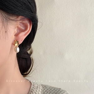 Close-up of French vintage baroque pearl earrings worn by a model in warm lighting