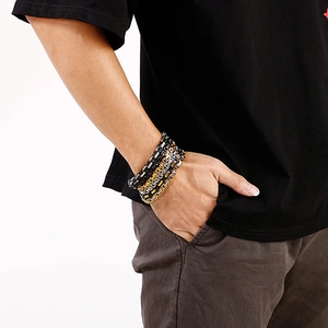 Macro detail of men's tri-color box chain bracelet in silver, gold and black stainless steel