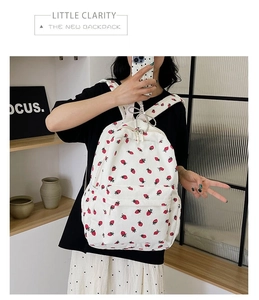 Detail of white corduroy backpack with red strawberry print and front zipper pocket
