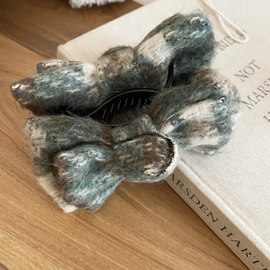 Detail of elegant plush bow hair clip in autumn colors on a wooden table with book