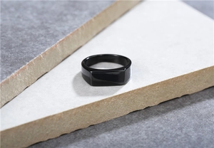 Macro shot of minimalist black stainless steel signet ring on textured stone