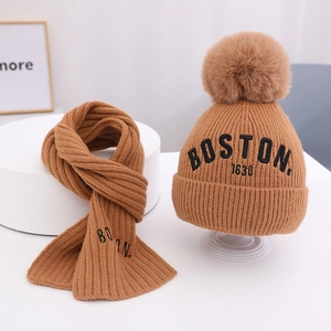 Detailansicht des kamelbraunen Stricksets für Babys mit Pelzpompon und Boston-Stickerei
