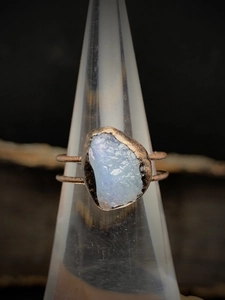 Detailed close-up of a vintage bronze ring with an irregular iridescent light blue raw stone