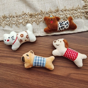 Detail view of plush animal brooches featuring varied fabric belly patterns on wood
