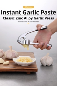 Zinc alloy garlic press in action mincing fresh cloves on a wooden board