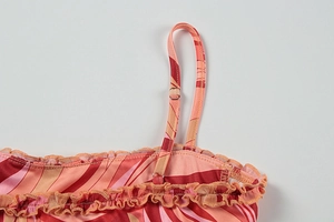 Detail of adjustable strap with silver buckle and ruffle edge on a printed dress