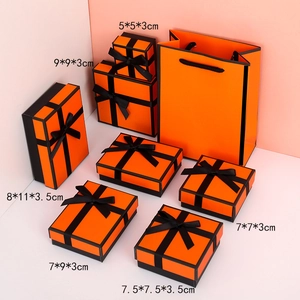 Orange jewelry gift boxes with black ribbon bows and matching paper bags in various sizes