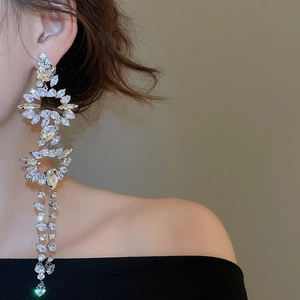 Close-up of dangling silver tassel earrings with marquise-cut zircon stones on a model