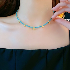 Détail du collier de perles turquoises avec pendentif doré sur modèle style boho