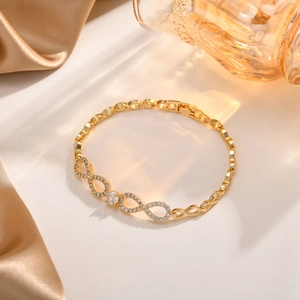 Detail eines Unendlichkeitssymbol-Armbands mit funkelnden Zirkonen auf vergoldeter Kette