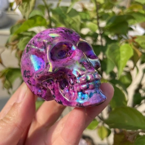 Handheld detail of a 7cm purple aura crystal skull with iridescent rainbow metallic finish