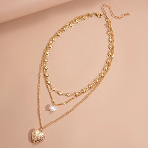 Close-up of triple-layered golden necklace with heart pendants and faux pearl details