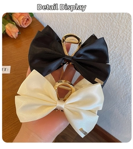 Detail of satin bow hair claws in black and cream with metal LOVELY charms and gold clips