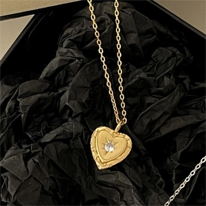 Detailed close-up of a heart-shaped gold necklace with a clear gemstone in a gift box