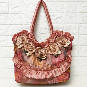 Detail of rose pink satin handbag with large 3D floral decorations and ruffled edges