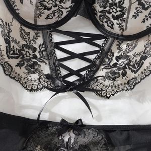 Detailed view of floral embroidery and satin cross-tie design on black and white lace lingerie