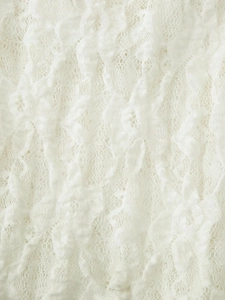 Close-up of white lace fabric detail with intricate floral knit patterns and soft texture