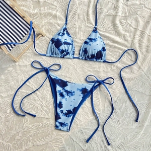 Detailed flat lay of blue tie-dye bikini set with side tie design on a white fabric background