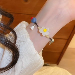 Gros plan détaillé du bracelet floral fait main avec pompon et perle en résine au poignet