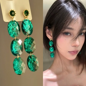 Vintage emerald geometric drop earrings with gold-tone setting shown on a model