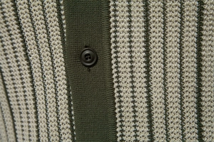 Macro shot of olive green striped knit polo fabric texture with black resin buttons