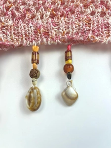 Detailed macro view of the bohemian knit hem with wooden beads and seashell charms