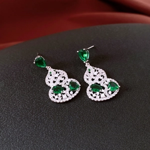 Macro detail of silver needle gourd earrings with green zircon and filigree pattern