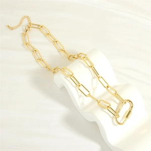 Detail of golden paperclip chain necklace with carabiner clasp on minimalist display