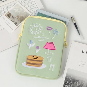 Detail of light green laptop sleeve featuring sunflower pancake embroidery and yellow zipper