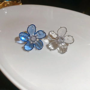 Macro shot of blue and white crystal flower ear clips with sparkling stone centers
