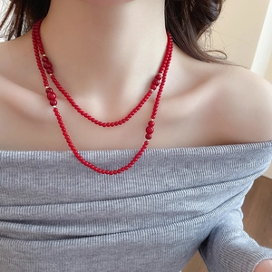 Detail of double-layer red crystal beaded necklace with golden spacers on a model