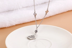 Macro view of silver fan-shaped necklace pendant with zircon in a ceramic dish