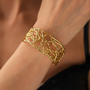 Close-up of a wide 18K gold-plated braided hollow cuff bracelet on a female wrist