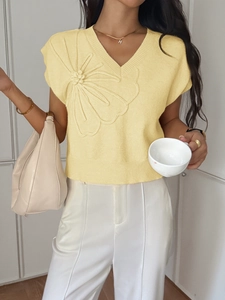 Detailed view of yellow V-neck knit vest with unique 3D floral decorations on fabric