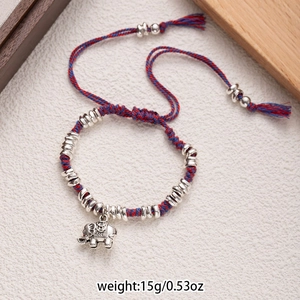 Detail of hand-woven cord bracelet with silver elephant pendant and ethnic bead accents