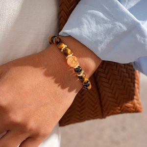 Close-up of beaded tiger eye bracelet with golden crown spacers on woman's wrist