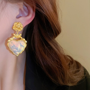 Détail de boucles d'oreilles vintage cœur fleur dorée avec résine irisée