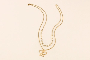Close-up of double-layered gold necklace featuring a hollow butterfly pendant and paperclip chain