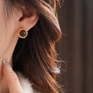 Nahaufnahme der Retro-Ohrstecker aus Gold mit braunem Tigerauge auf dem Modellohr