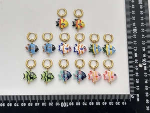 Measurement photo of colorful ceramic fish earrings with gold hoops on white background