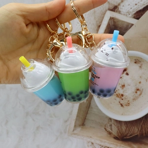 Handheld view of acrylic bubble tea cat keychains in blue, green and pink colors