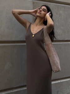 Detail of a dark brown knitted maxi dress with a V-neckline and chic gold pendant necklace