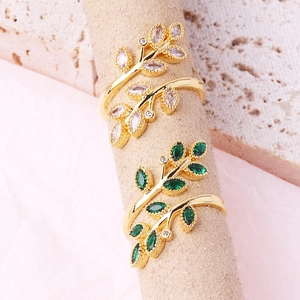 Golden wheat leaf cross rings with white and green marquise zircons in elegant display
