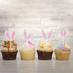Close-up of four silver glitter bunny ear cake toppers on cupcakes for Easter party