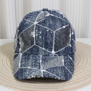 Close-up of sparkling silver sequins and geometric white stitching on blue denim cap
