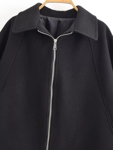 Detail of a black wool-blend jacket showing the silver metal zipper and lapel collar