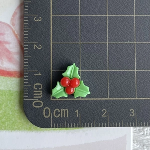 Macro detail of 1.5cm resin holly berry ornament on a metric scale cutting mat